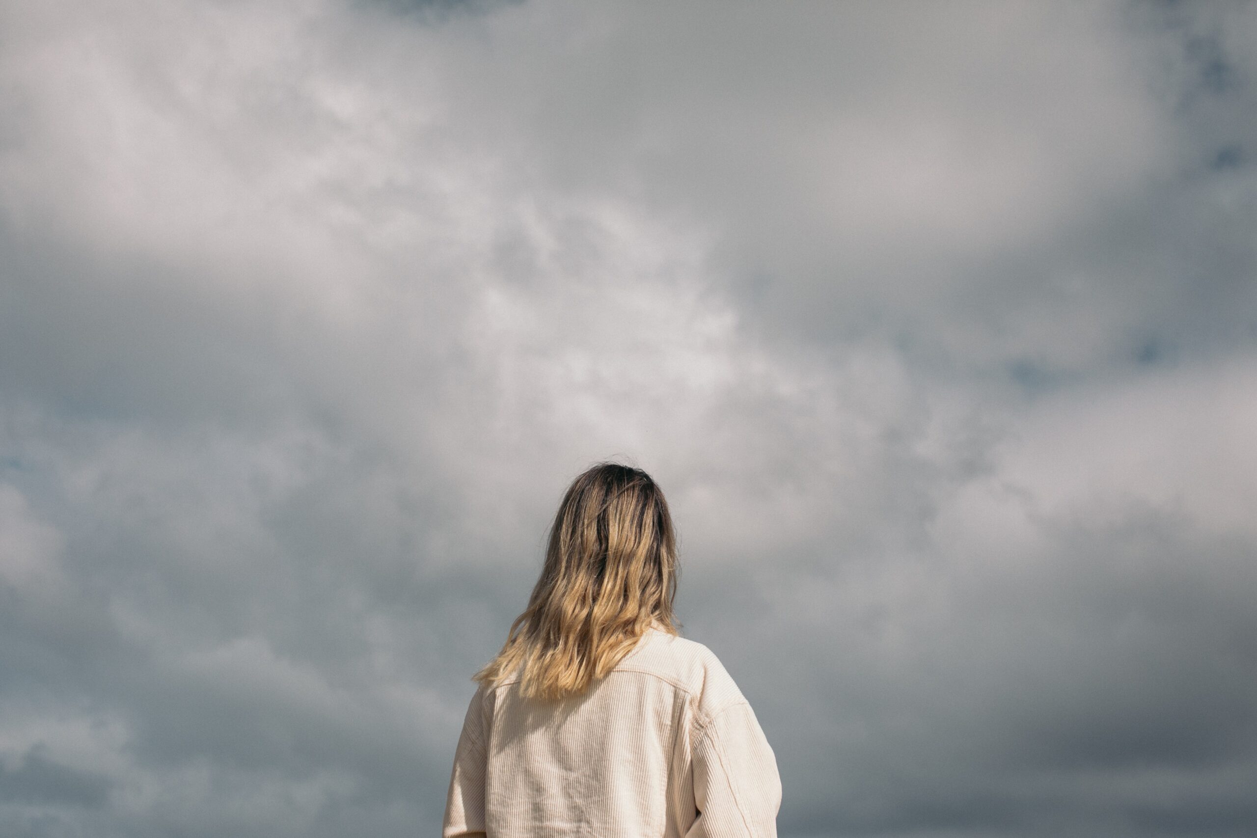 back of woman staring at a stormy sky