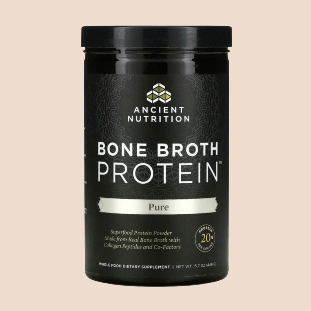 A black container of Ancient Nutrition Bone Broth Protein powder, labelled “Pure,” standing upright against a soft beige background.