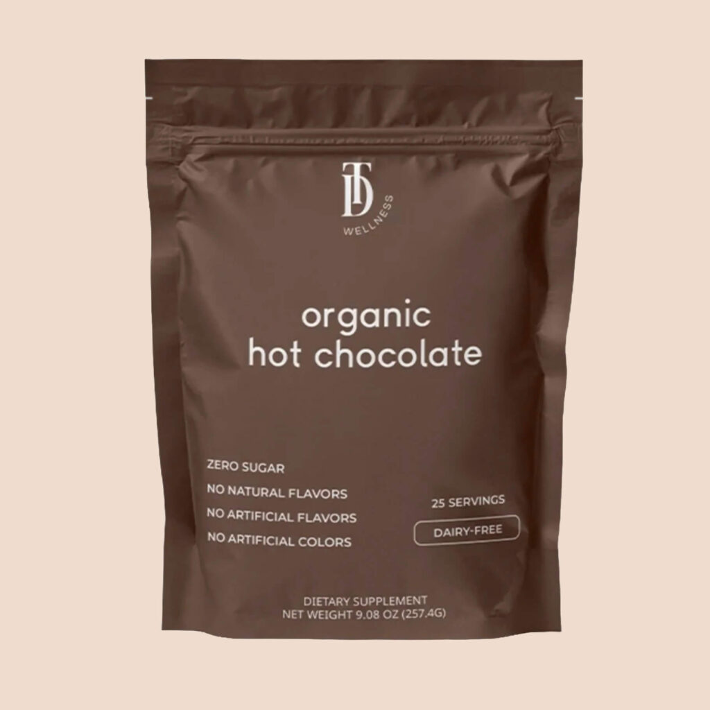 A brown resealable pouch labelled “Organic Hot Chocolate” from TD Wellness, photographed against a neutral beige background.